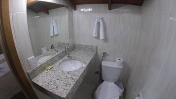Un baño con lavamanos de mármol, inodoro y espejo.