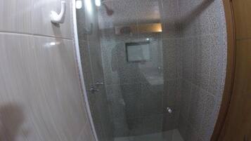 A glass-enclosed shower stall with a tiled wall and a small window.