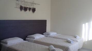 Habitación de hotel con tres camas individuales, cabecera oscura y una obra de arte colgada en la pared.