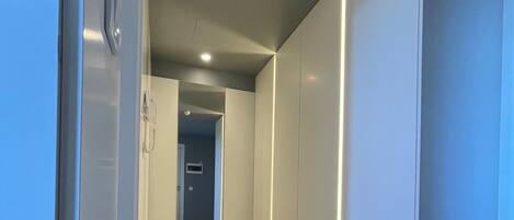 A hallway with a concrete floor, white walls, and a ceiling light.