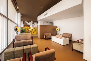Eine moderne Lobby mit Sitzbereichen, einem Empfangstisch und einem Schild mit der Aufschrift 'SNACKS'.