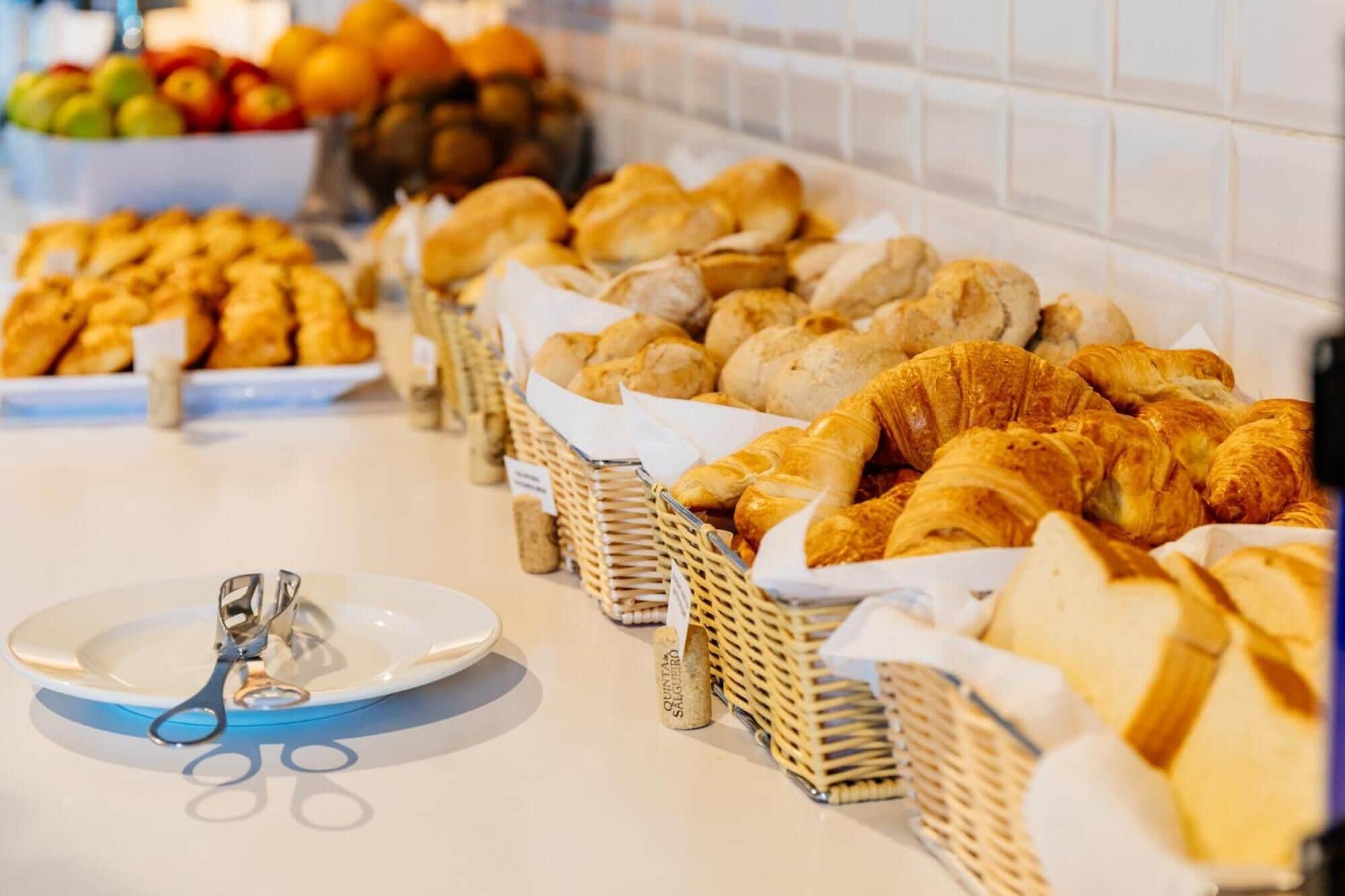 A buffet with various breads and pastries, including croissants and baguettes, arranged in baskets.