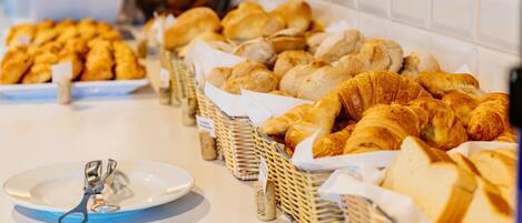 A buffet with various breads and pastries, including croissants and baguettes, arranged in baskets.