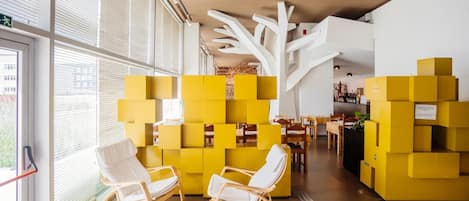 Un interior moderno con muebles modulares amarillos, sillones roqueros blancos y una estructura blanca que recuerda a un árbol.