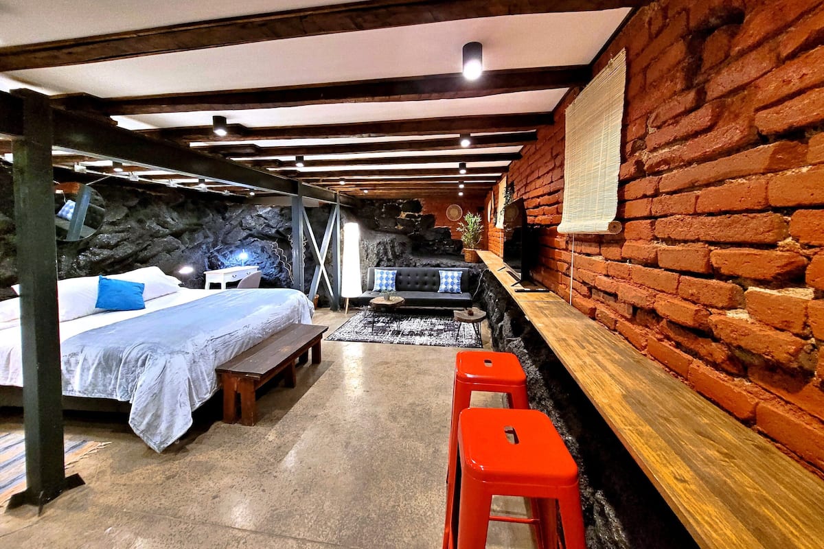 Um quarto rústico com uma cama, um sofá e um banco de madeira.