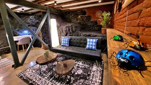Una habitación acogedora con un sofá negro, una mesa de centro de madera y una alfombra estampada.
