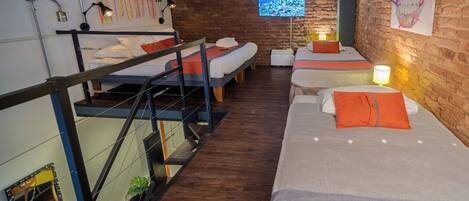 A room with bunk beds, a TV, and a brick wall.