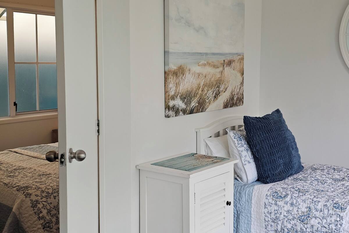 Une chambre à coucher comprenant un lit, une table de chevet, un tableau accroché au mur et une fenêtre à vitre dépolie.