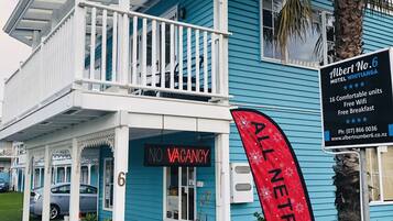 Um motel com varanda, um aviso de 'No Vacancy' e uma bandeira da 'Netflix'.