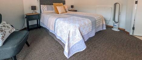 Een slaapkamer met een bed, nachtkastjes, een stoel en kunst aan de muur.