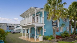 A two-story building with a balcony, a sign indicating it is a motel, and a parked car in front. - Albert Number 6 Motel (Whitianga)