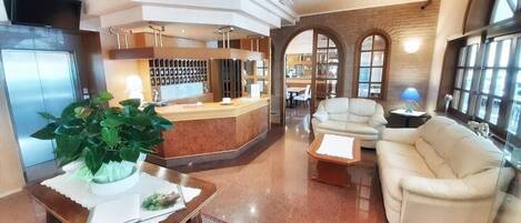 A spacious lobby with a reception desk, seating area, and a large window.