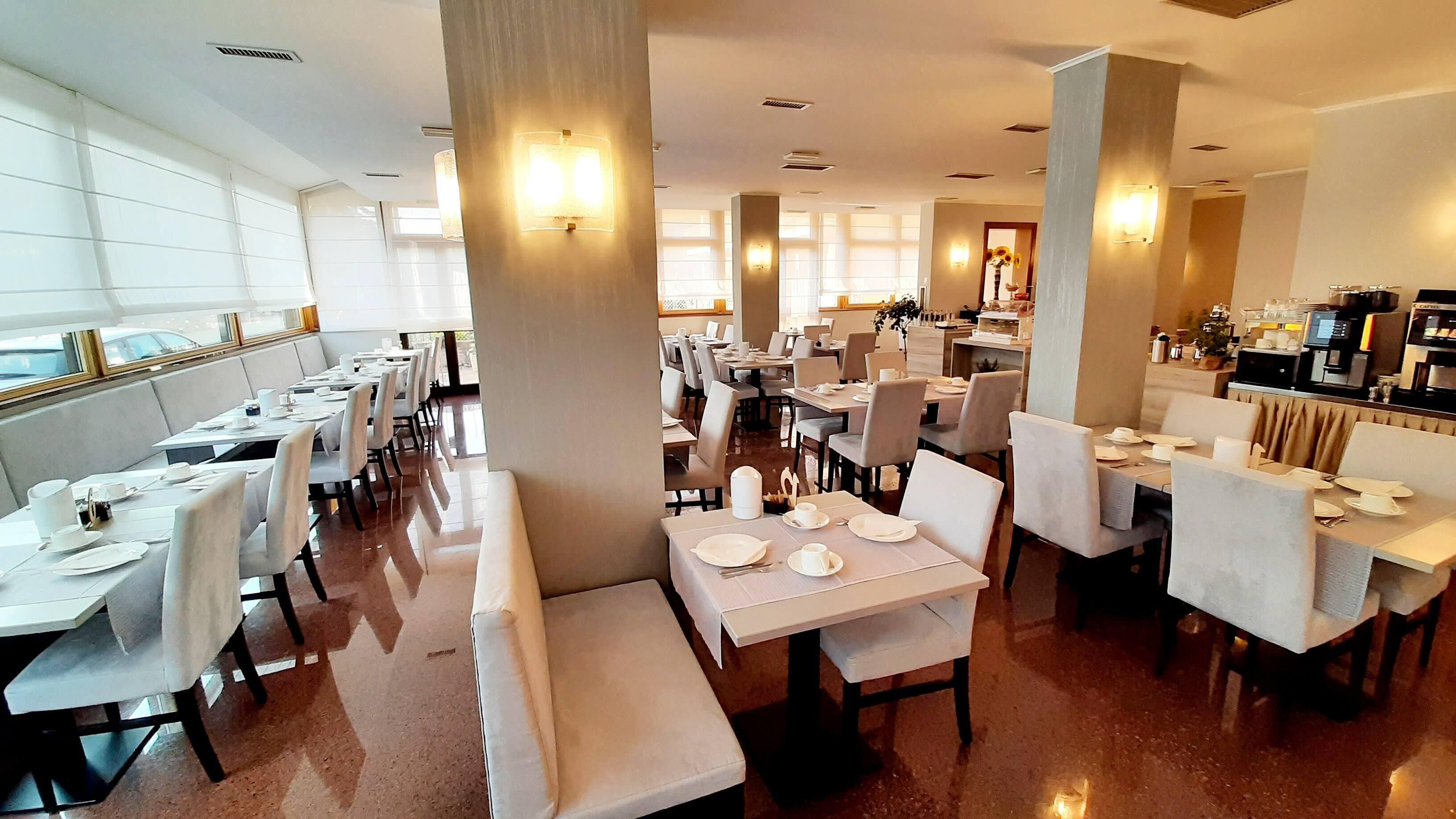 Un vaste espace dédié à la salle à manger, avec de nombreuses tables et chaises, de grandes fenêtres et un aménagement intérieur moderne.