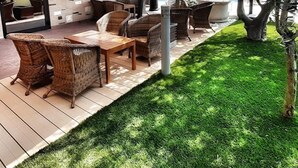 Un patio al aire libre con mobiliario de mimbre, una piscina y una zona de estar cubierta.