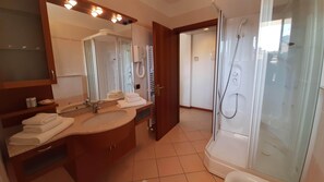 Moderni kylpyhuone, jossa on suuri peili, kaksi pesuallasta, suihku ja wc.