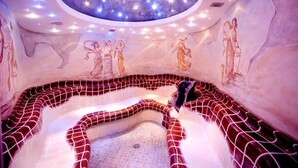 Un spa con techo estrellado, paredes de mosaico y una bañera de hidromasaje central.