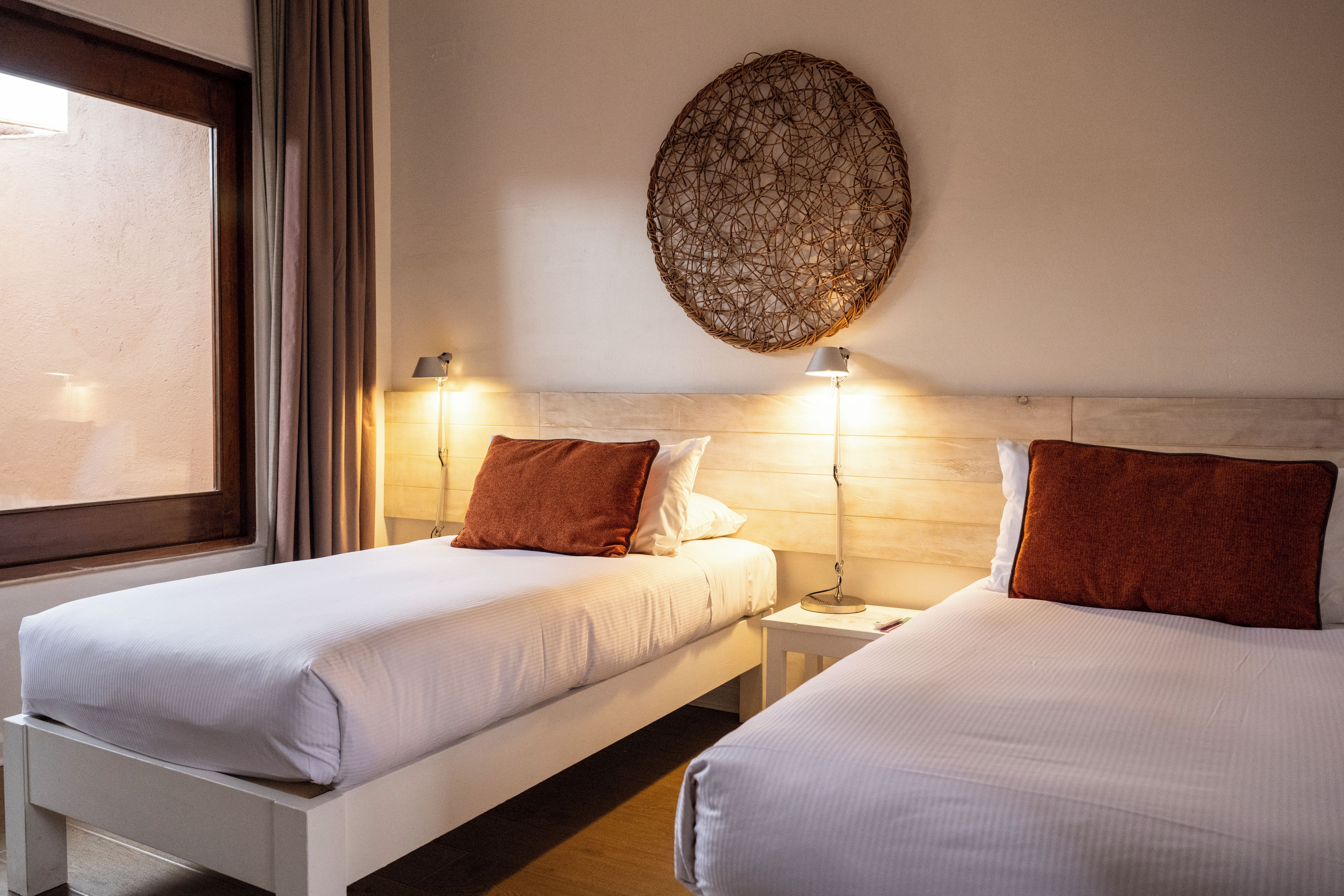 A hotel room with two beds, a large window, and a decorative wall piece.