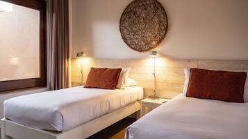 A hotel room with two beds, a large window, and a decorative wall piece.