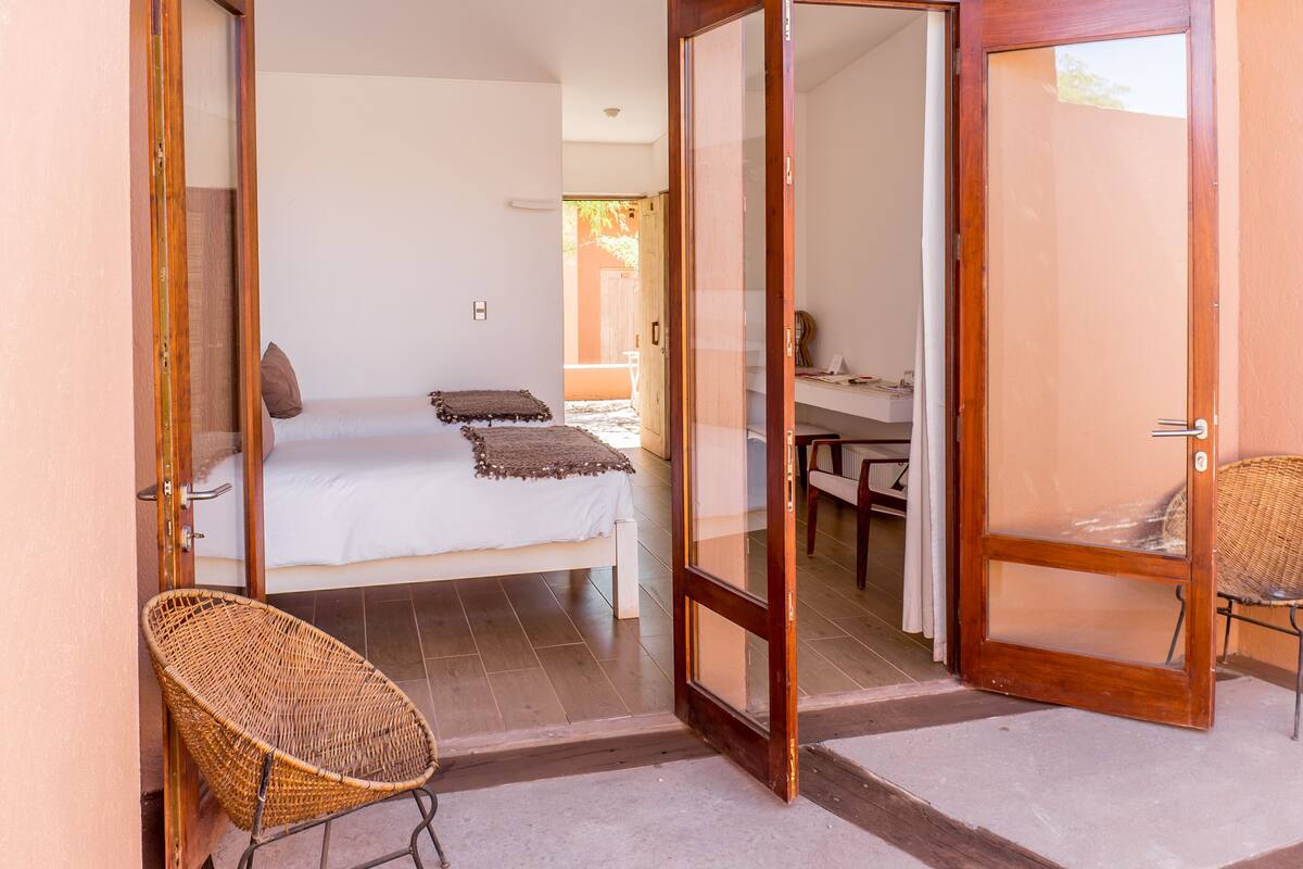 Een slaapkamer met een bed, een stoel en een schuifpui naar een balkon.