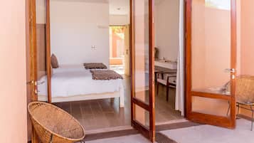 Un dormitorio con cama, una silla y un ventanal corredera que da a un balcón.