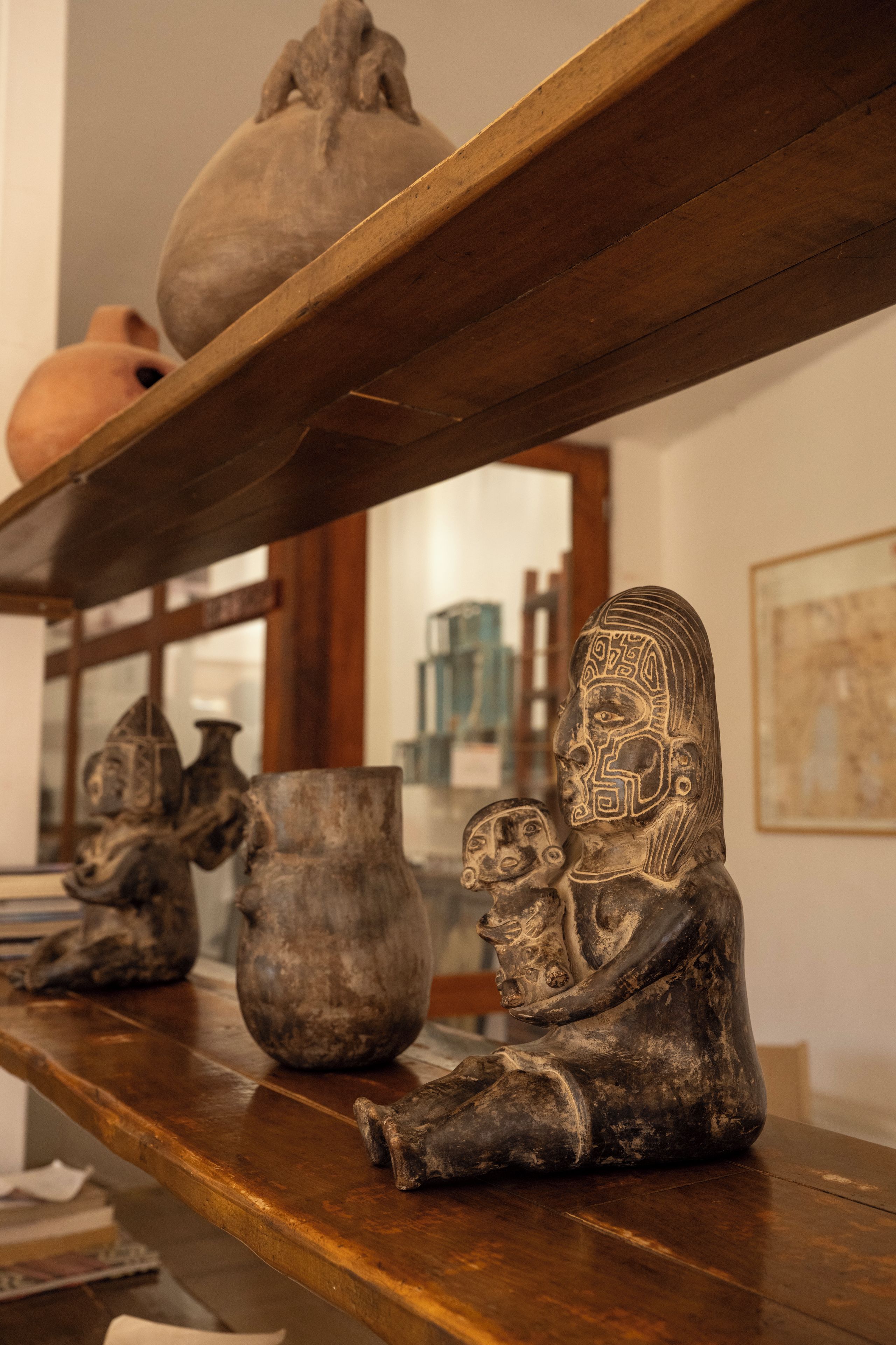 Une étagère en bois sur laquelle sont disposés divers objets en céramique et une sculpture.