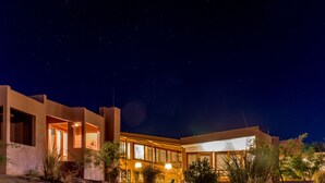 A modern building with large windows and a well-lit entrance at night. - Noi Casa Atacama (San Pedro de Atacama)