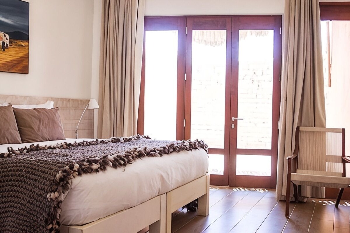 Une chambre à coucher avec un lit, une chaise et une porte donnant sur l’extérieur.