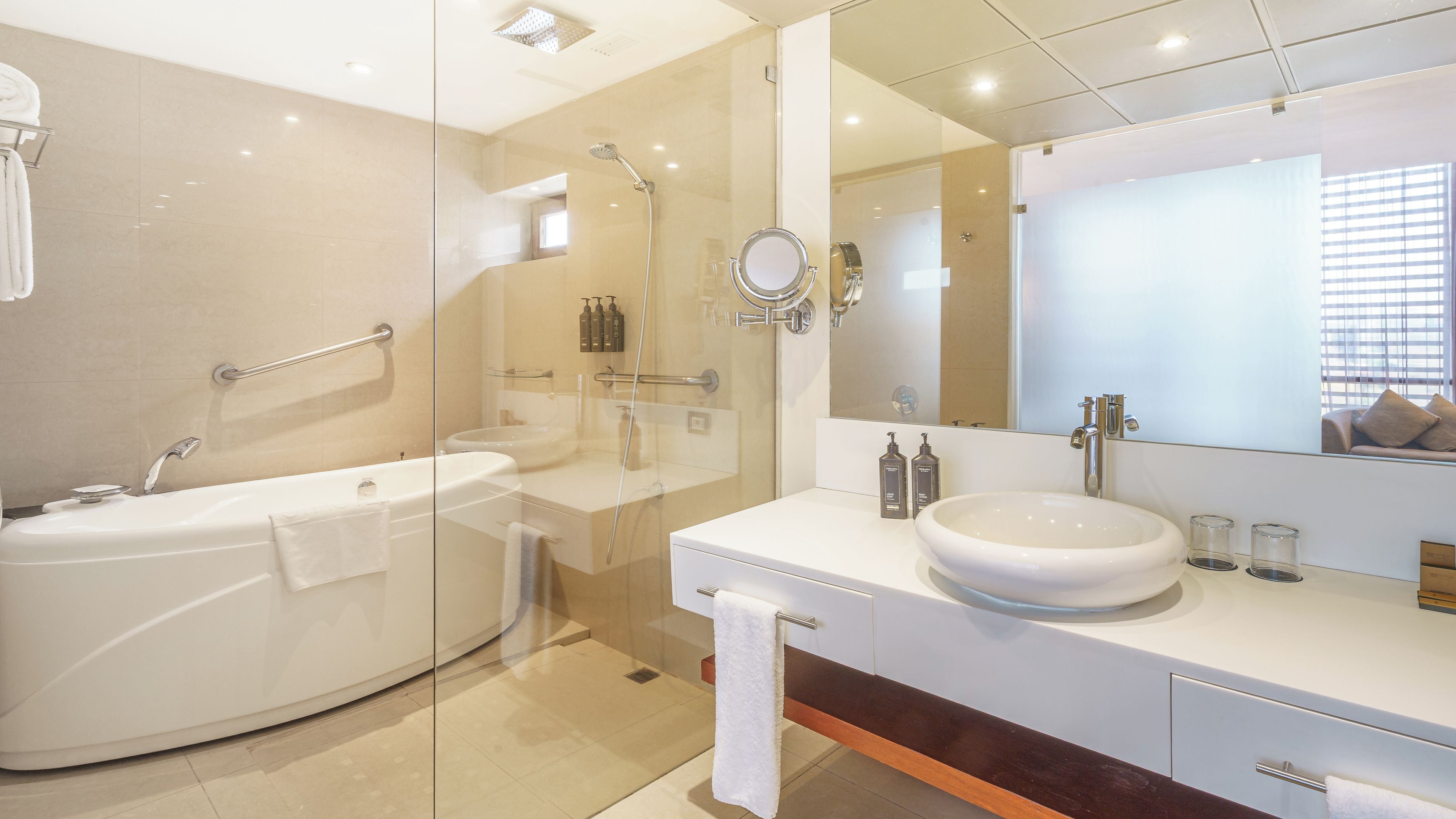Un baño moderno con ducha envuelta en vidrio, una bañera independiente y un tocador con un espejo grande.