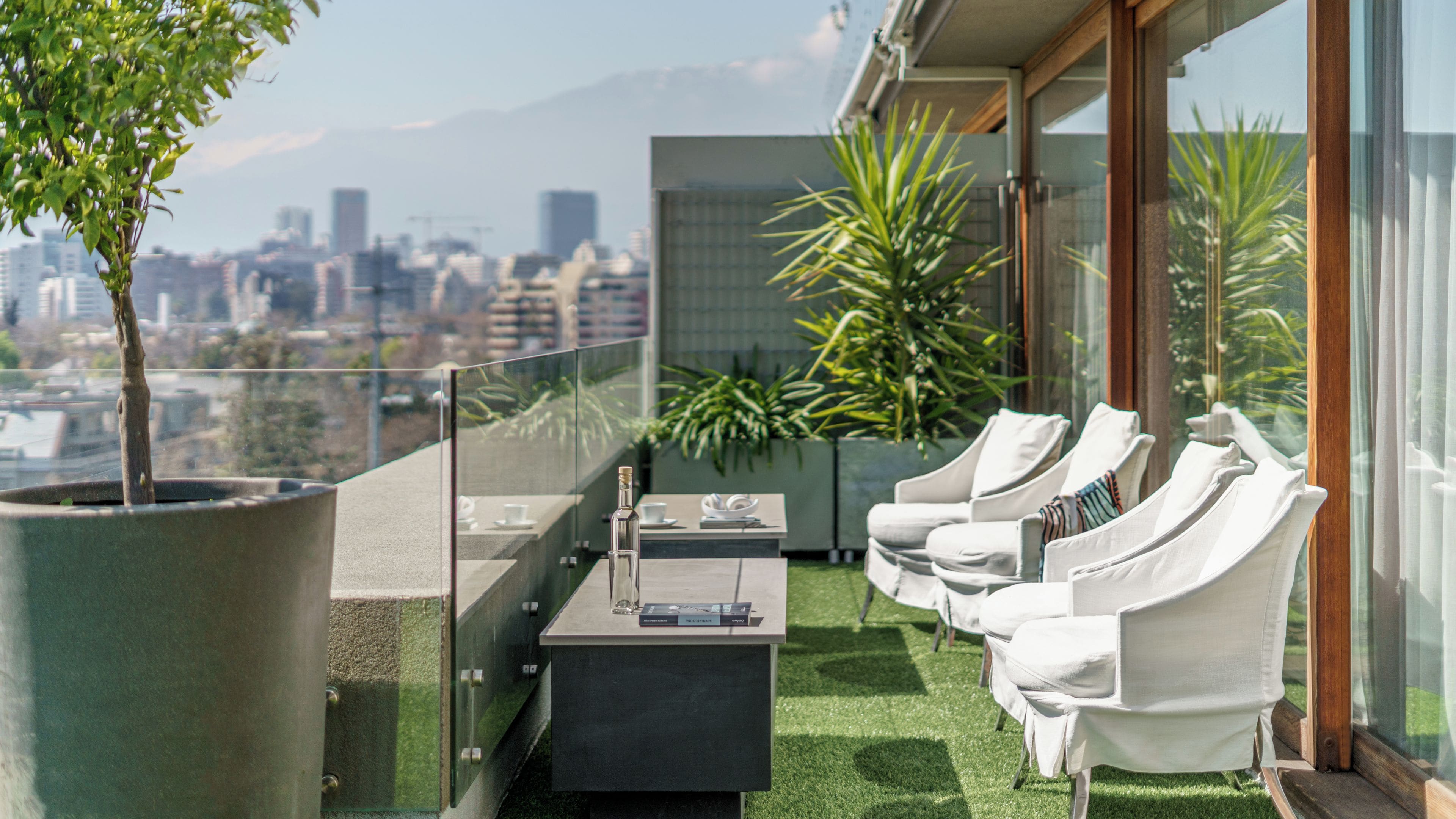 Eine Dachterrasse mit Blick auf die Stadt, Sitzgelegenheiten im Freien und einem Blumentopf.