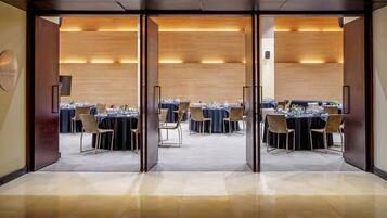 A conference room with multiple tables set for dining, equipped with chairs and table settings.