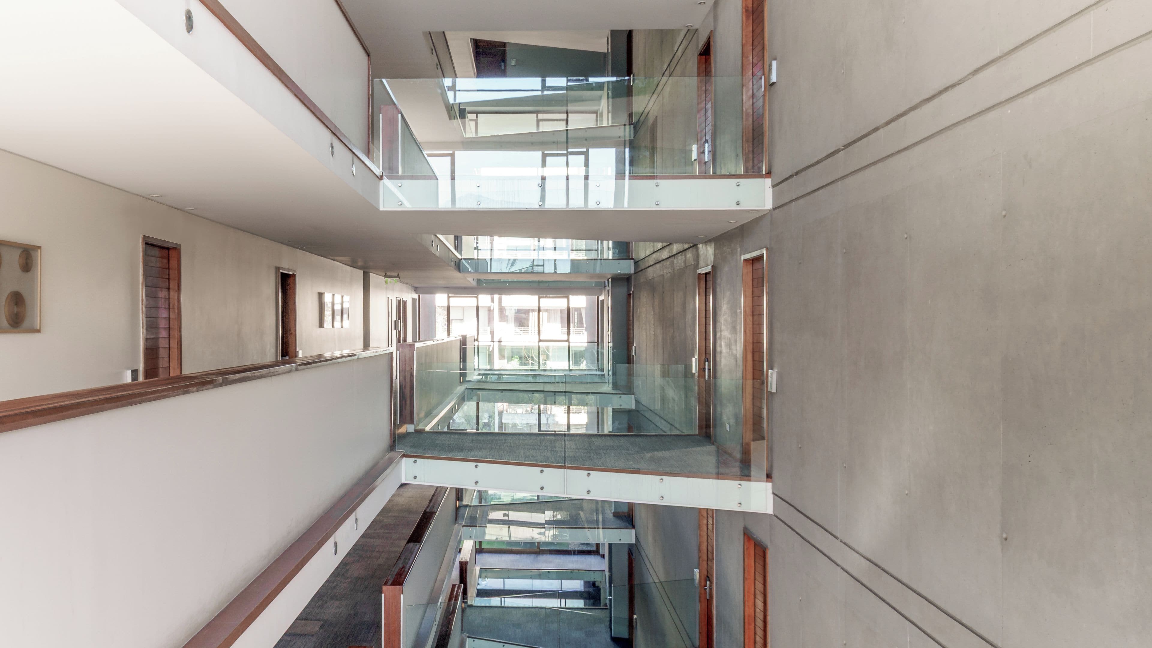 Un couloir à plusieurs niveaux, doté de rampes en verre et d’une conception architecturale moderne.