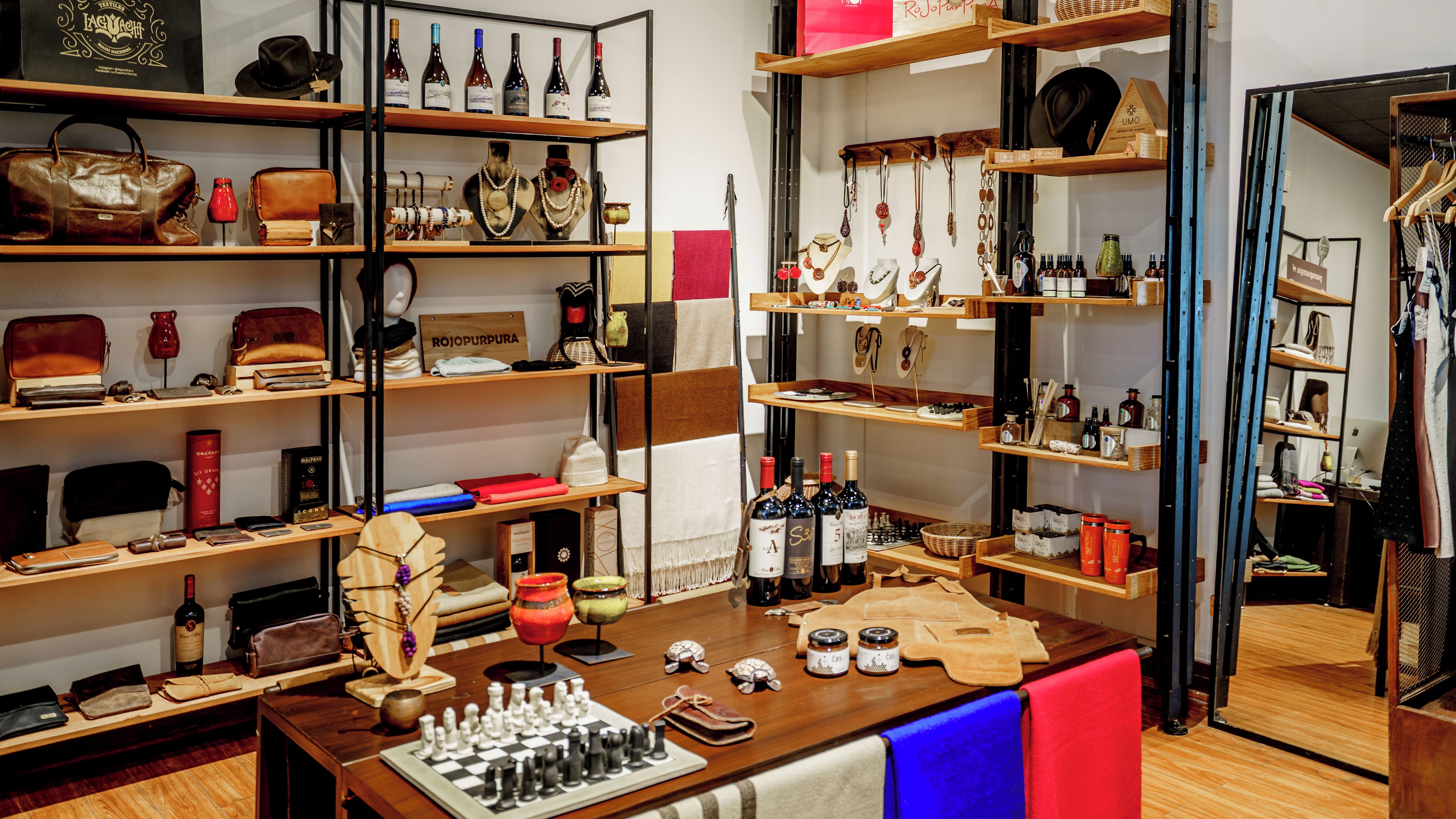 Una tienda boutique con estantes llenos de joyería, bolsos y botellas de vino.