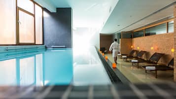 Una piscina cubierta, una piscina al aire libre, tumbonas