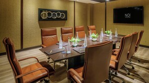 A conference room with a long table, brown leather chairs, water bottles, and a TV screen displaying 'NOI VITACURA'. - Noi Vitacura (Santiago)