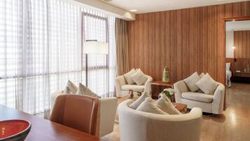 A hotel room with a wooden panel wall, a sofa set, a dining table, and a lamp.