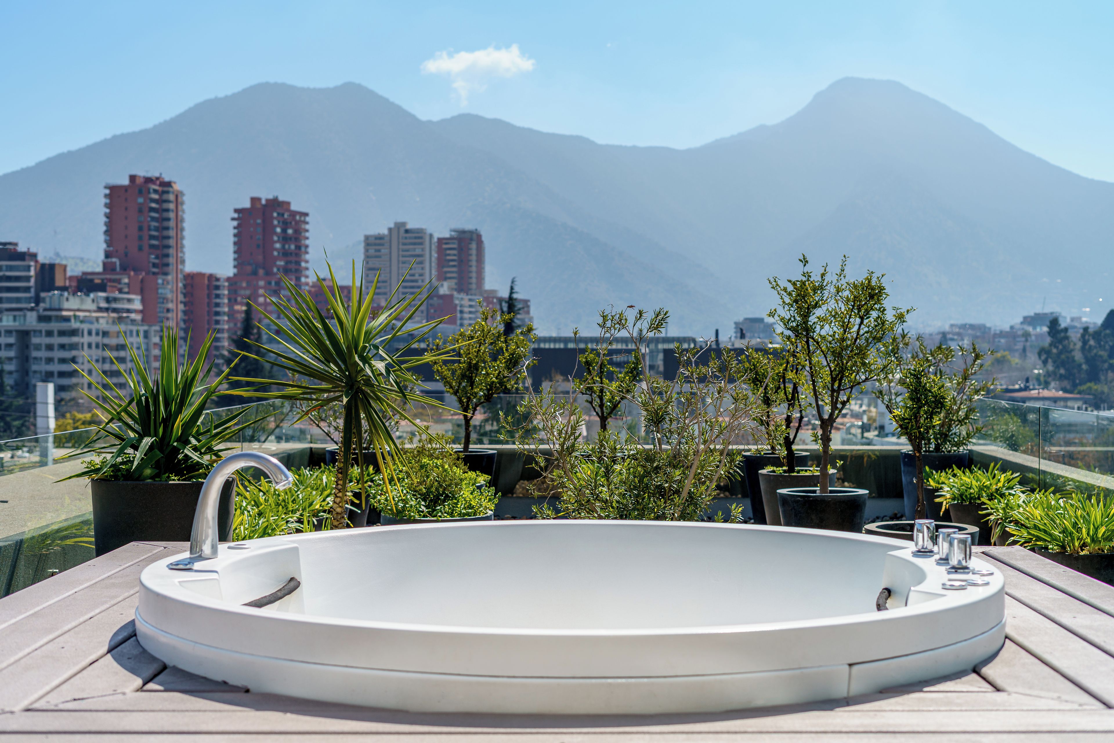 Un jacuzzi sur le toit, avec une vue sur la ville et les montagnes en arrière-plan.