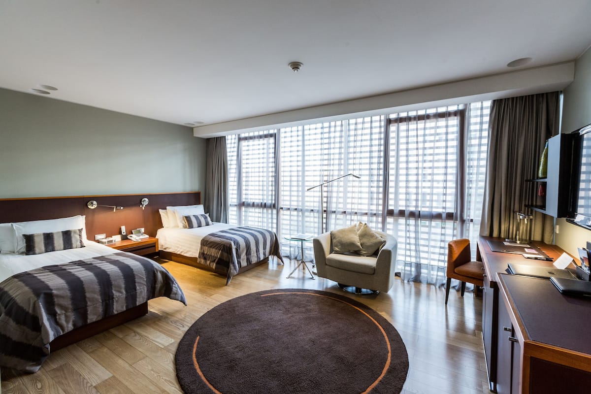 Une chambre d’hôtel avec deux lits, un bureau, une chaise et un téléviseur.