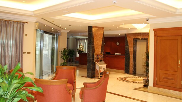 A hotel lobby with a reception desk, a large pillar, and seating area. - Al Madina Suites Doha (Doha)