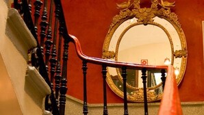 Una escalera con una pared roja y un espejo con marco dorado.