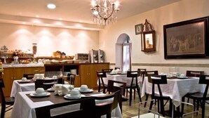 Comedor con mesas dispuestas para el servicio, un bufé al fondo y una araña.