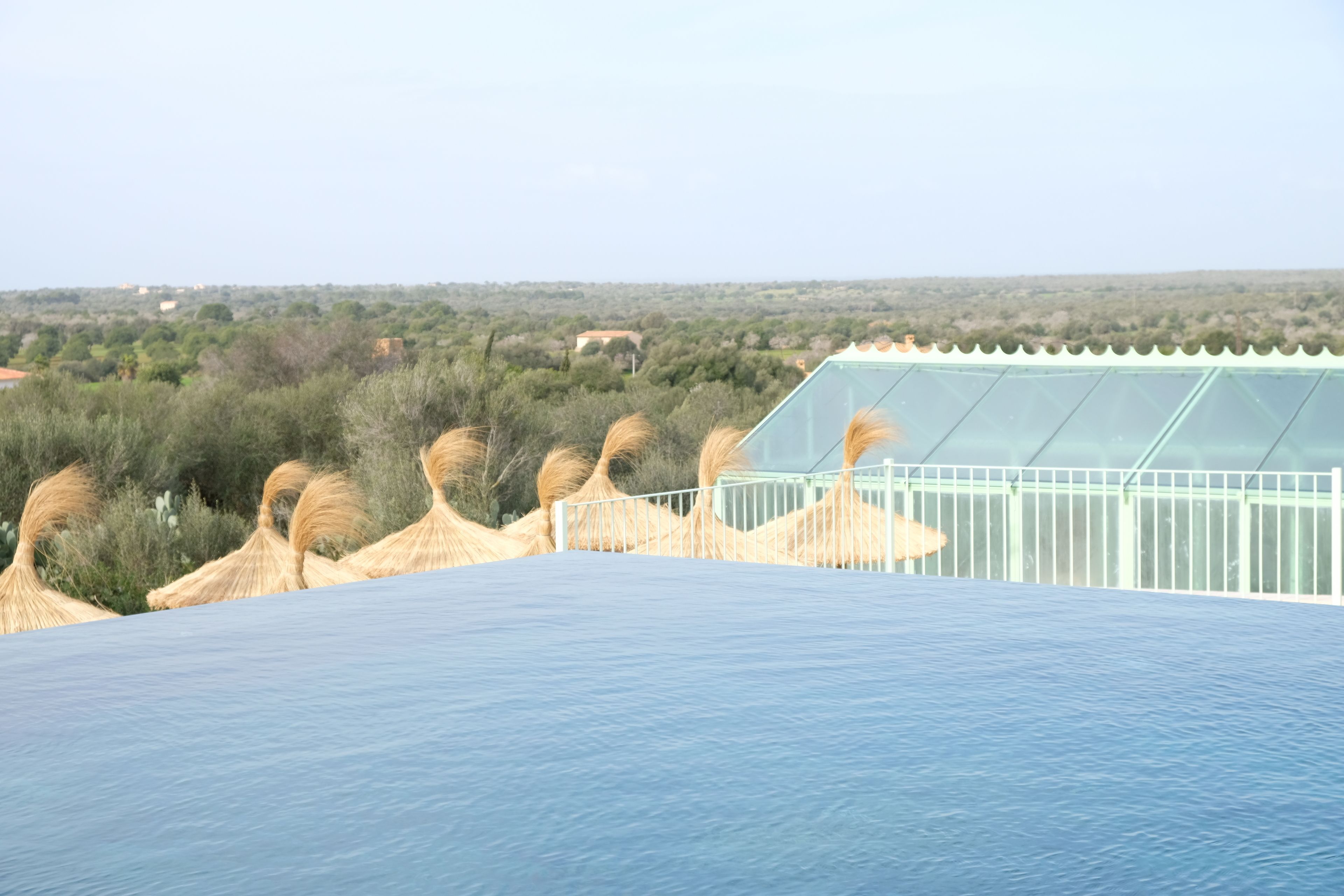 A pool with a clear view of the surrounding landscape, including vegetation and distant buildings.