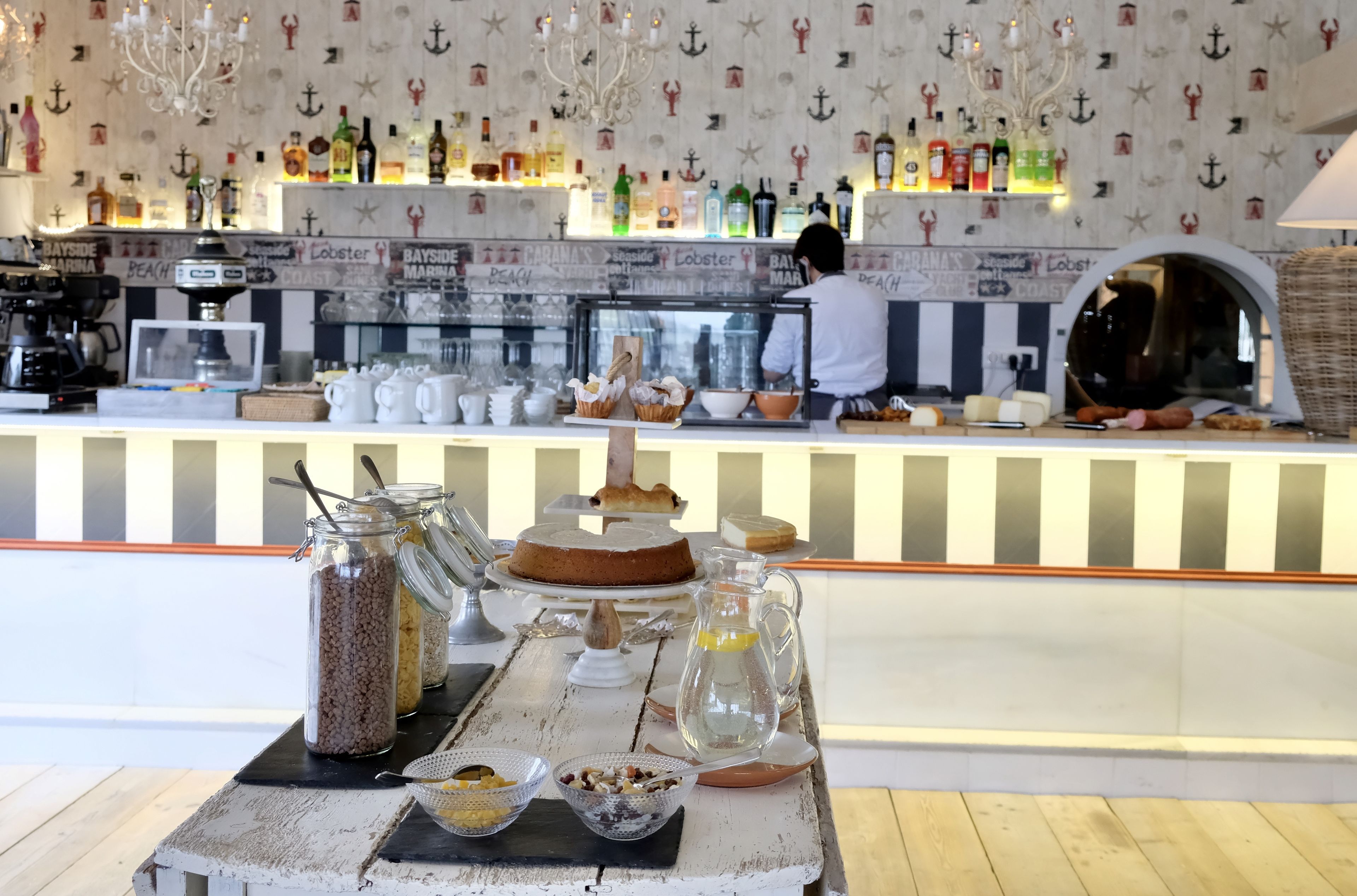Un espace bar avec un comptoir où sont exposées différentes bouteilles et un chef qui prépare les plats.