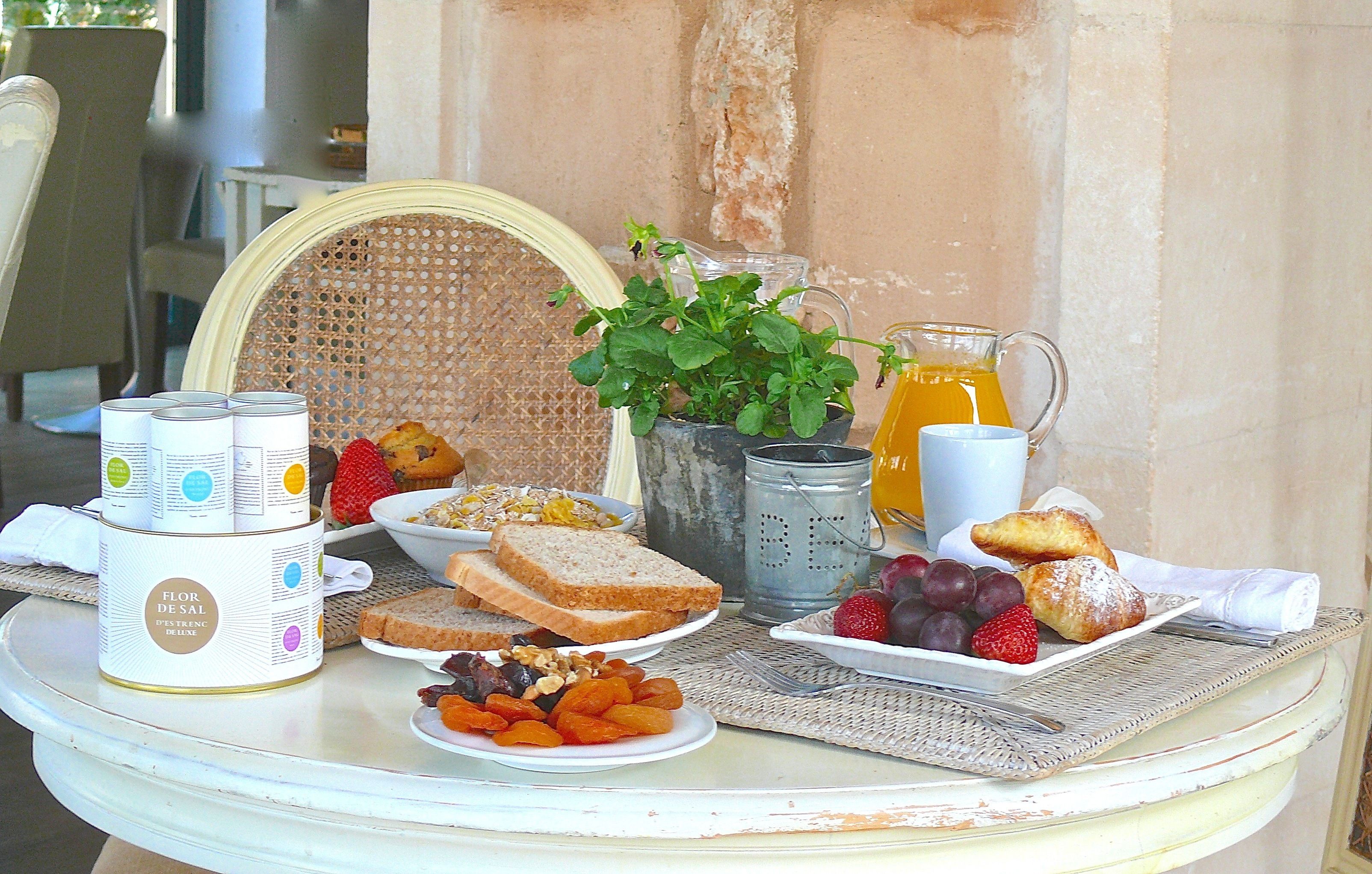 A breakfast table with various food items, a pitcher of orange juice, and a canister labeled "Flor de Sal".