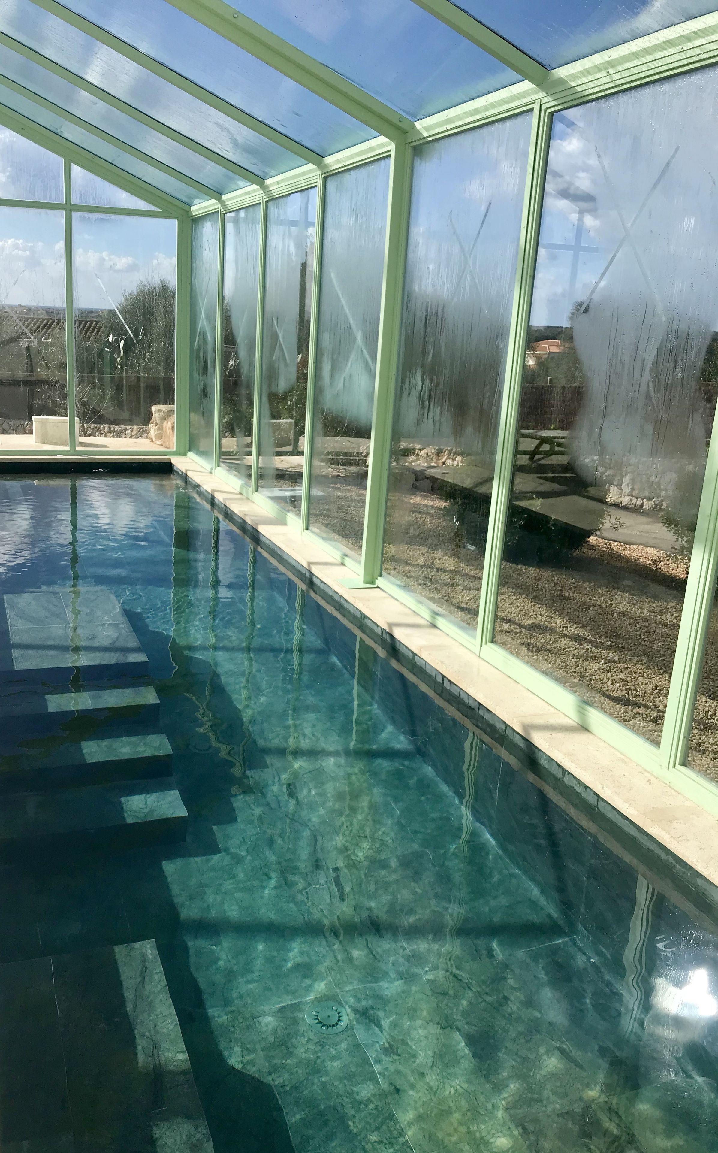 Une piscine aux eaux cristallines, entourée de parois en verre, offrant une vue sur les environs.