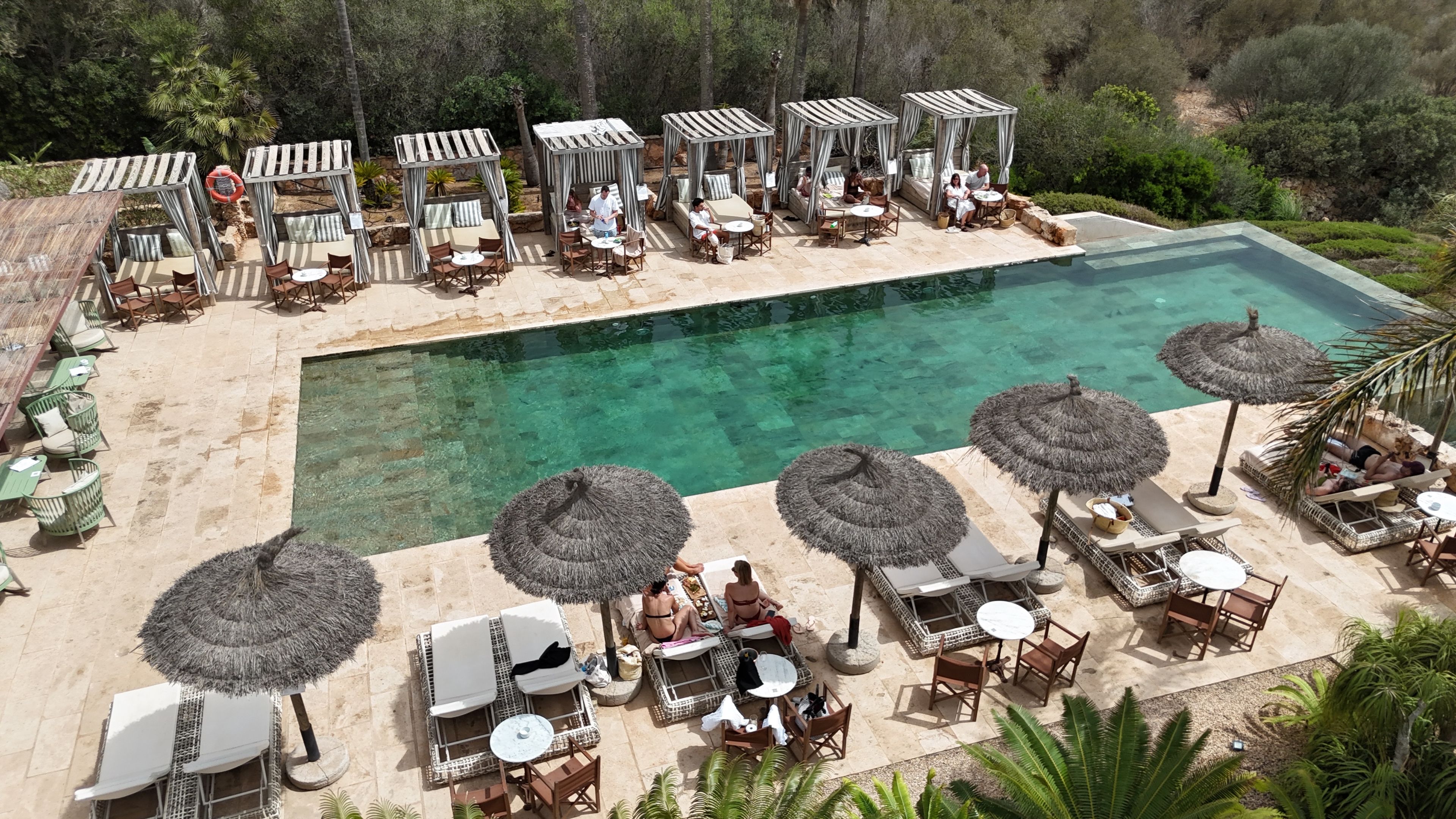 Ein Poolbereich mit Liegestühlen, Sonnenschirmen und klarem Wasser.