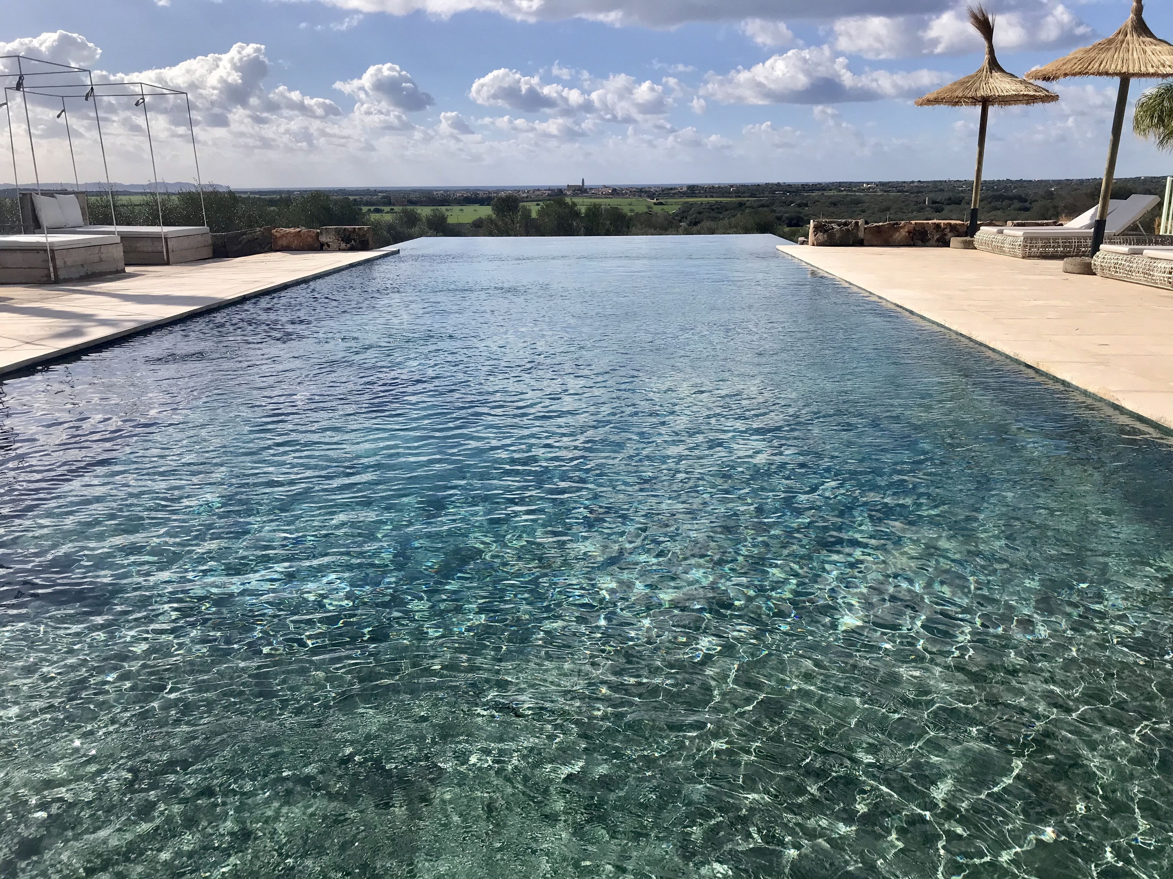 A clear swimming pool with a view of the countryside.