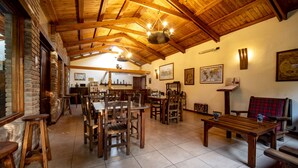 A rustic dining area with wooden tables and chairs, a brick wall, and a wooden ceiling. - Lujan de Cuyo B&B (Luján de Cuyo)