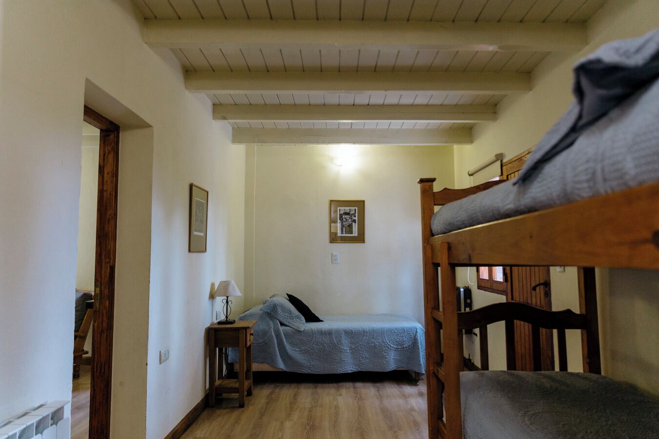 Habitació petita i acollidora amb una lliterà doble, una taula de nit amb una làmpada i un quadre a la paret.
