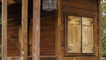 A wooden cabin with a porch, a lantern hanging above, and a brick base.