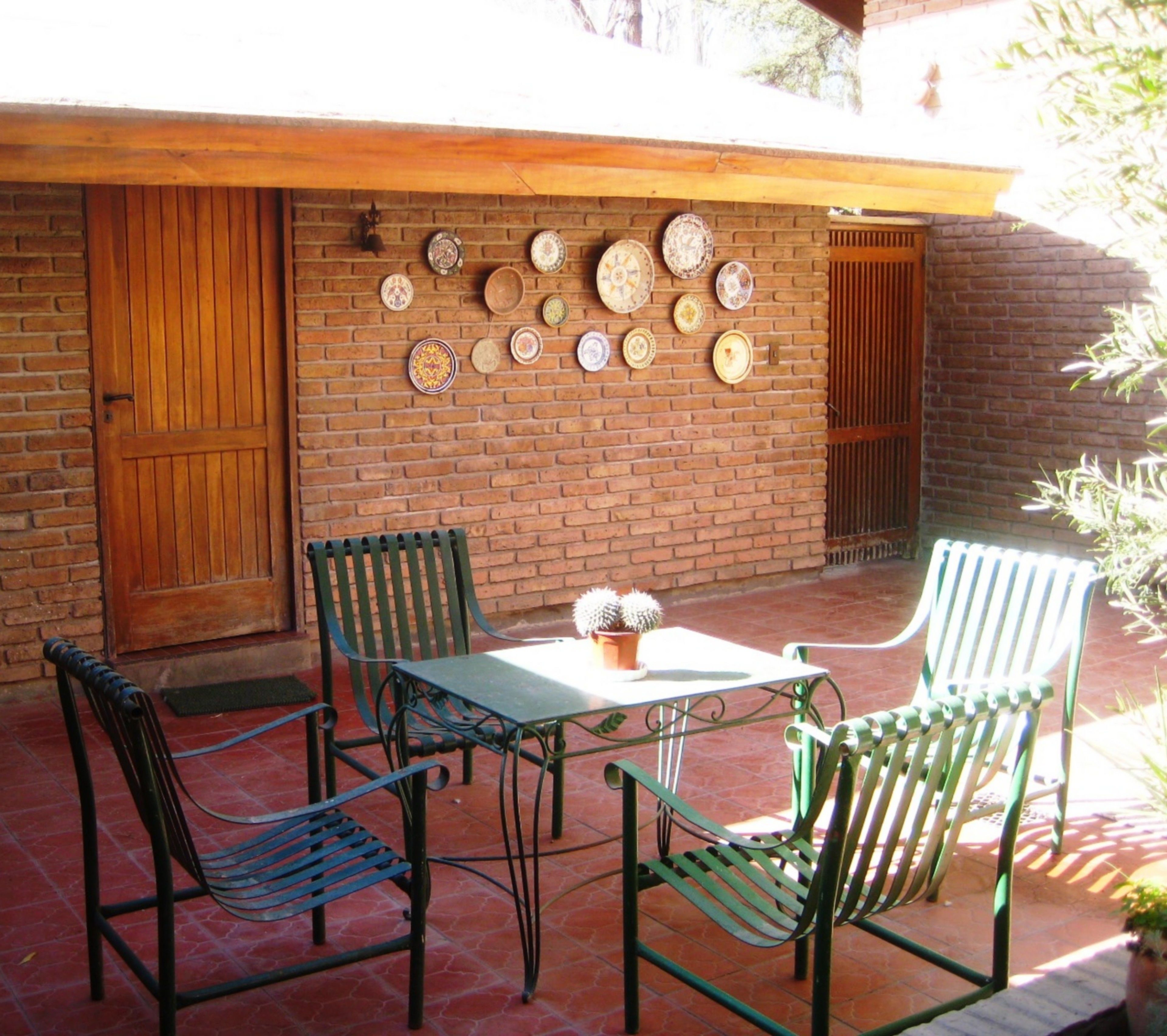 A patio with a brick wall, a wooden door, and a table with chairs.